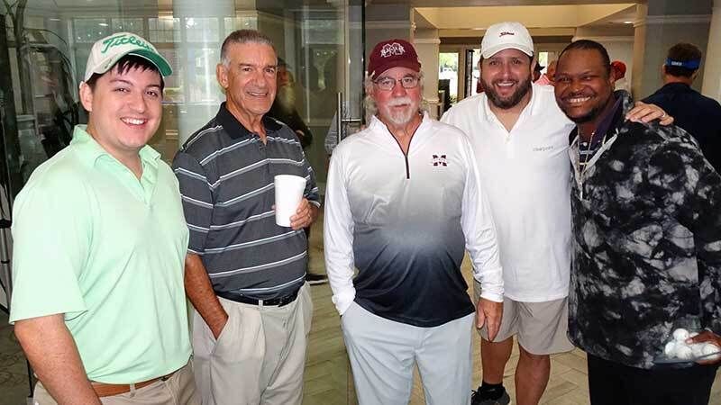 A team of five posing together at the clubhouse